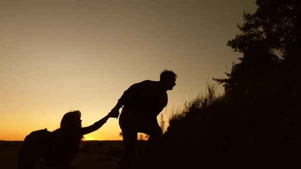 Tourists go down from the goy in the sunset, holding hands. male traveler holds the hand of a female traveler going down from top of the hill. teamwork of business people. Happy family on vacation. — Stock Photo, Image