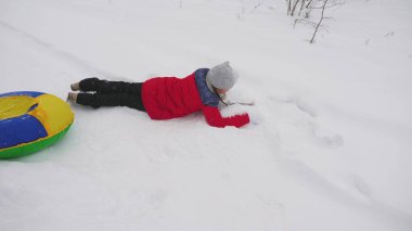Mutlu baba, beyaz karlı bir yolda kızakla bir çocuğa biniyor. Noel tatilleri. Yetişkinler ve çocuklar için eğlenceli bir oyun. Mutlu aile kavramı. Bir genç Tubing 'e biniyor.