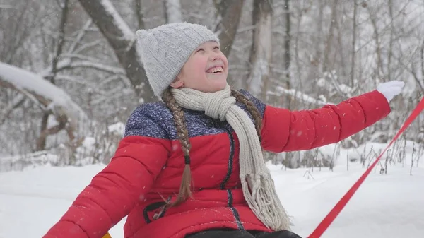 Ein glückliches Mädchen rollt auf Schläuchen entlang einer weißen, schneebedeckten Straße und lacht im Flug der Freiheit. Weihnachtsferien. ein lustiges Spiel für Erwachsene und Kinder. das Konzept einer glücklichen Familie — Stockfoto