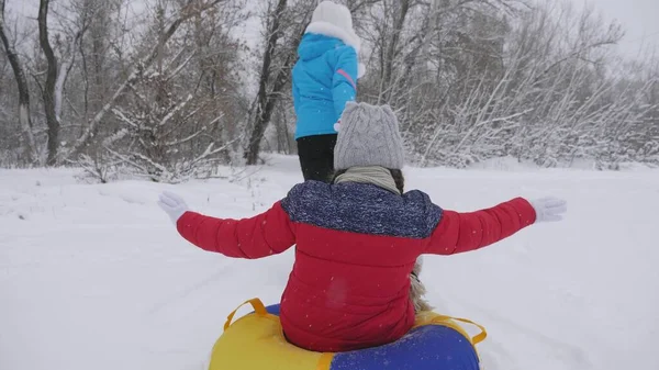 Familie wintervakantie. kind en moeder sleeën in de sneeuw. Dochter en moeder spelen op kerstvakantie in het winterpark. gelukkige kindertijd concept — Stockfoto