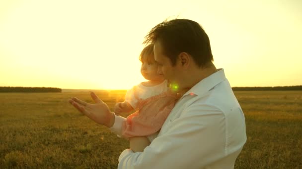 A boldog család és gyermekkor fogalma. Apa játszik a lányaival a parkban pihen. Apa és anya játszik egy kislánnyal a karjaiban naplementekor. család séta egy gyerekkel naplementekor. — Stock videók