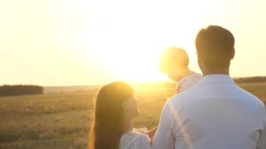 Kız parkta dinlenmek ile baba. mutlu aile ve çocukluk konsepti. Aile gün batımında bebekle oynuyor. Baba ve annem gün batımında kollarında kızı ile yürümek.