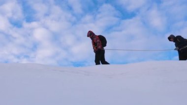 Tırmanışçılar güvenlik halatıyla birbiri ardına karlı zirveye tırmanıyorlar. Kış yolcularından oluşan bir ekip kışın dağlara seyahat eder. Kışın dağcı takım çalışması