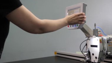 İşçi, tablet bilgisayar kullanarak bir dikiş makinesini Cnc ile programlıyor. Operatör cnc makinesini ayarlar.