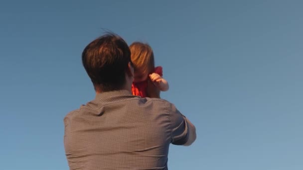 O pai atira a filha para o céu azul. O pai brinca com uma criança pequena. família feliz jogando à noite contra o céu. O pai vomita o bebé, o miúdo sorri. Movimento lento. família feliz — Vídeo de Stock