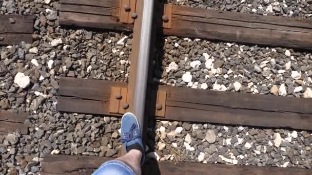 As pernas do viajante vão nos laços ferroviários. close-up. passos turísticos sobre os dormentes. o passageiro ficou para trás do comboio. Movimento lento — Vídeo de Stock