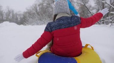Çocuk ve anne karda kayıyorlar. Kız ve anne Noel tatillerinde kış parkında oynuyorlar. Aile kış tatili. Mutlu çocukluk kavramı