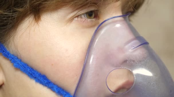 Une fille malade dans un masque respire un vaporisateur. Femme avec un masque bleu d'hôpital. Inspirez des vapeurs des voies respiratoires dans les poumons. Traitement de la toux. Gros plan — Video