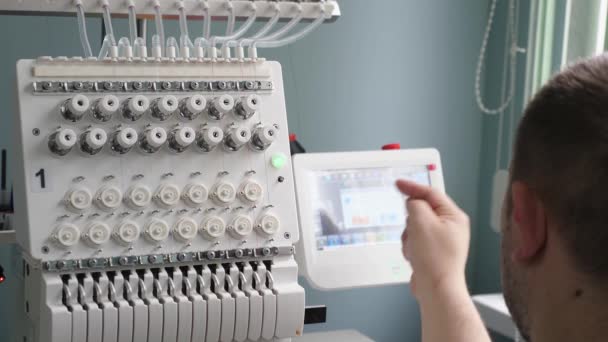 Worker is programming a sewing machine with a CNC using a tablet computer. The operator sets up the cnc machine. — Stock Video