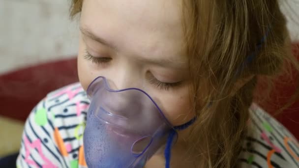 El niño con el comprimido está enfermo y respira a través de un inhalador. Primer plano. niña pequeña tratada con una máscara de inhalación en su cara en el hospital. El niño pequeño trata la gripe inhalando vapor de inhalación . — Vídeo de stock