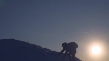 Mutlu gezgin dağ zirvesine tırmanır. Turist yüksek karlı dağda duruyor, ellerini sallıyor ve gün batımında zafere seviniyor. Dağcı kışın dağlara yolculuk eder. Alpenist yürüyüş yapıyor.