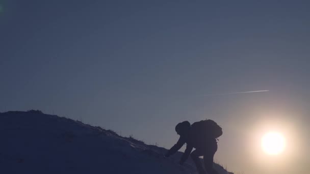 Щасливий мандрівник піднімається на гору. Туристи стоять на високій сніговій горі, махає руками і радіє перемозі на заході сонця. Зимою альпініст їде в гори. Подорожі алпіністів — стокове відео