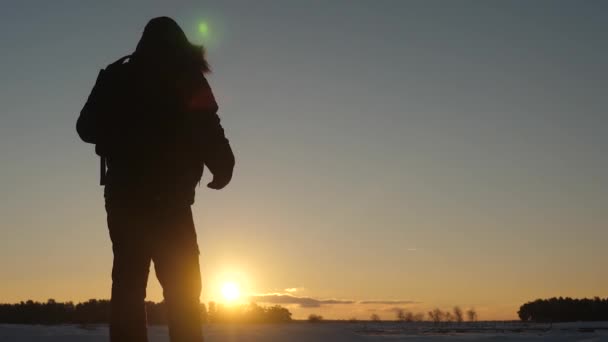 Manliga turister med ryggsäckar klättra till toppen på bakgrund av vackra himmel och sol. resenär med ryggsäck går på snöiga kulle i solnedgången mot den blå himlen strålar. — Stockvideo