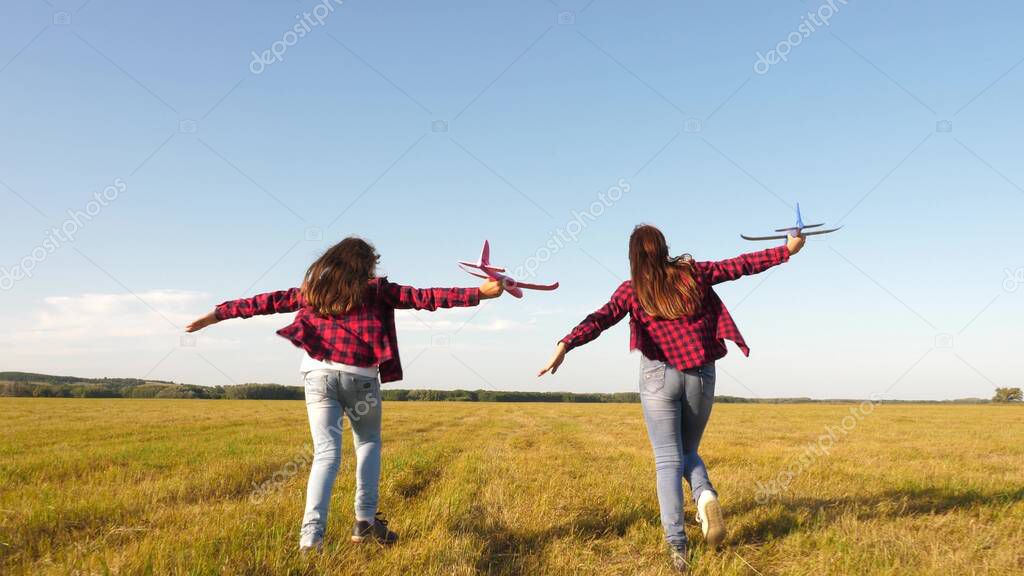 children play toy airplane. teenagers want to become pilot and astronaut. Happy girls run with toy plane at sunset on field. concept of a happy childhood. Girls dream of flying and becoming a pilot.