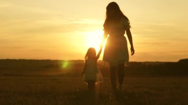 Küçük kız ve anne el ele tutuşarak sahada dolaşıyorlar. Bebek annesinin elini tutuyor. Mutlu aile akşamları şehir dışına çıkar. Anne ve bebek parkta dinleniyorlar. Çocuk çayırda annesiyle oynuyor.