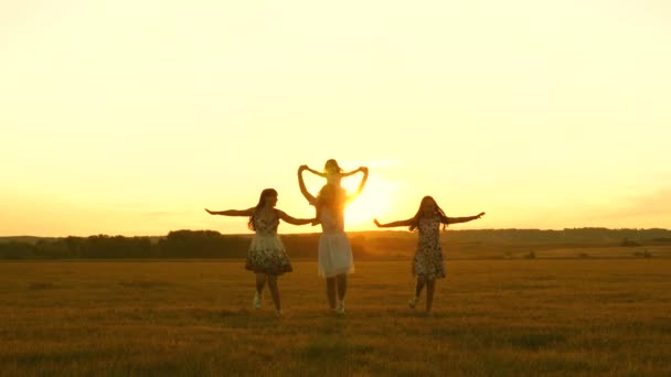 Szczęśliwego dzieciństwa. Szczęśliwa młoda rodzina z dzieckiem biegnie po polu o zachodzie słońca. Matka i córki spacerują w parku i bawią się na łące w słońcu. koncepcja życia dużej rodziny — Wideo stockowe