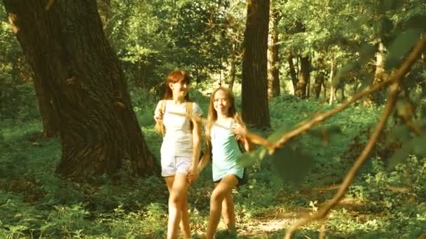 Giovani ragazze viaggiatori con zaini corrono attraverso le boscaglie nella foresta. Una escursionista cammina nella foresta. Ragazza escursionista felice nel parco estivo. adolescente ragazza avventure in vacanza . — Video Stock