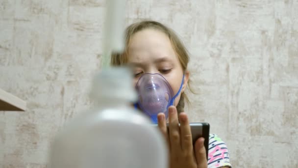 Criança com comprimido está doente e respira através de um inalador. close-up. menina tratada com uma máscara inalatória em seu rosto no hospital. A criança trata a gripe inalando vapor inalatório . — Vídeo de Stock