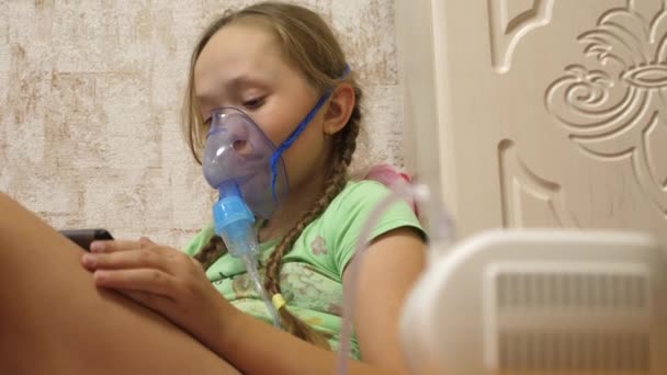 Kind met tablet is ziek en ademt via een inhalator. close-up. klein meisje behandeld met een inhalatiemasker op haar gezicht in het ziekenhuis. Peuter behandelt griep door inhalatiedamp in te ademen. — Stockvideo