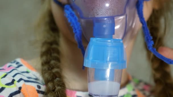 Enfant avec comprimé est malade et respire par un inhalateur. Gros plan. petite fille traitée avec un masque d'inhalation sur le visage à l'hôpital. Tout-petit soigne la grippe en inhalant de la vapeur d'inhalation . — Video