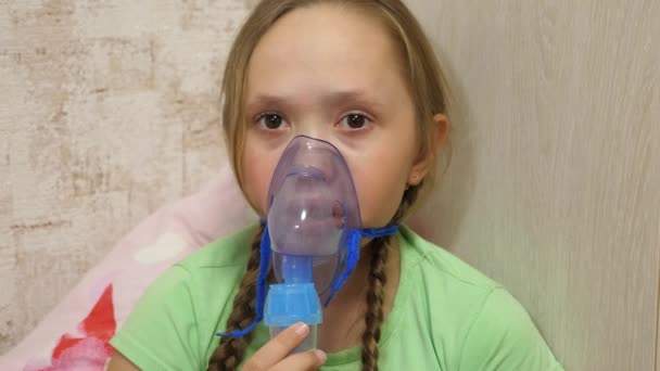 Child with tablet is sick and breathes through an inhaler. close-up. little girl treated with an inhalation mask on her face in hospital. Toddler treats flu by inhaling inhalation vapor. — Stock Video