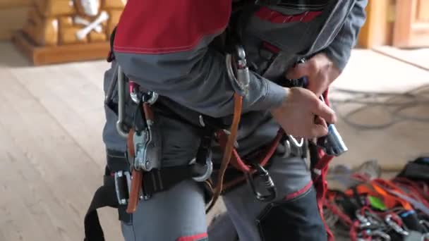 Ο βιομηχανικός ορειβάτης διαθέτει εξοπλισμό για εργασίες σε μεγάλο υψόμετρο. στα καραμπίνερς της ζώνης ορειβασίας. — Αρχείο Βίντεο
