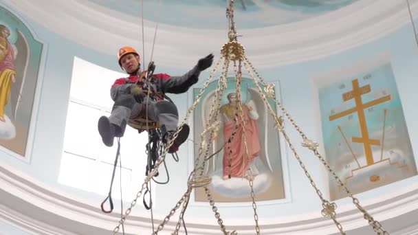 Un arrampicatore industriale su una scala sta preparando una corda per l'attrezzatura di sollevamento. un lavoratore con un casco protettivo lavora un nodo su una corda . — Video Stock