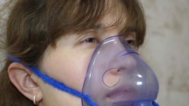 Больной девушка в маске вдыхает баллончик от спрея. Женщина в синей больничной маске. Вдыхайте пар из дыхательных путей в легкие. Лечение кашля. Крупный план — стоковое видео