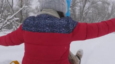 Mutlu çocukluk kavramı. Aile kış tatili. Çocuk ve anne karda kayıyorlar. Kız ve anne Noel tatillerinde kış parkında oynuyorlar..