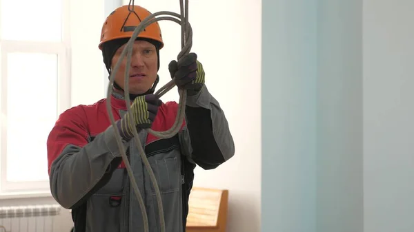 Industrial climber knits a rope for lifting equipment. a worker in a protective helmet knits a knot on a rope. — Stock Photo, Image