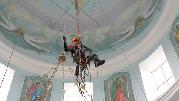 Un grimpeur industriel sur une échelle prépare une corde pour l'équipement de levage. un travailleur portant un casque de protection tricote un nœud sur une corde . — Photo