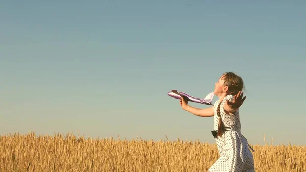 Glückliches Mädchen rennt mit einem Spielzeugflugzeug auf einem Feld im Sonnenuntergang. Kinder spielen Spielzeugflugzeug. Teenager träumt davon zu fliegen und Pilot zu werden. Das Mädchen will Pilotin und Astronautin werden. Zeitlupe — Stockfoto