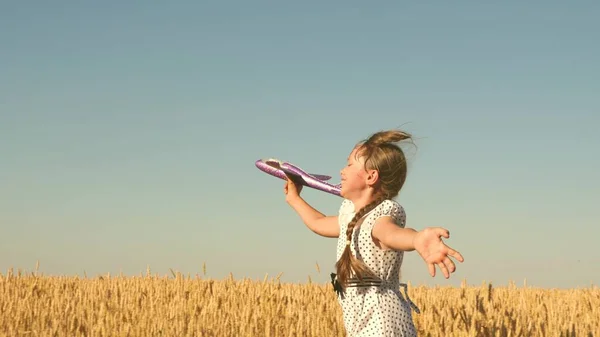 Glückliches Mädchen rennt mit einem Spielzeugflugzeug auf einem Feld im Sonnenuntergang. Kinder spielen Spielzeugflugzeug. Teenager träumt davon zu fliegen und Pilot zu werden. Das Mädchen will Pilotin und Astronautin werden. Zeitlupe — Stockfoto