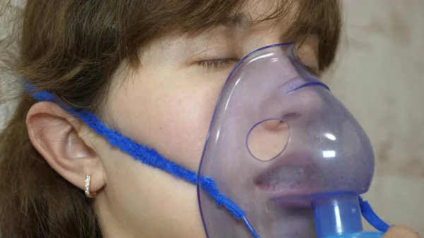 Vrouw wordt behandeld met een inhalatiemasker op haar gezicht in een ziekenhuis. ziek meisje wordt ingeademd door een vernevelaar die op de bank zit. Een vrouw met een masker. Adem dampen in voor de luchtwegen in de longen. Hoestbehandeling — Stockfoto