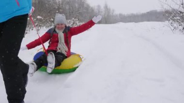 Mutlu çocukluk kavramı. Aile kış tatili. Çocuk ve anne karda kayıyorlar. Kız ve anne Noel tatillerinde kış parkında oynuyorlar..