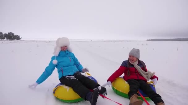 Children and mom ride sledding in winter. mother and daughter play on christmas vacation in winter park. The concept of happy childhood. happy family concept. — Stock Video