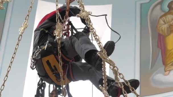 Industrial climber in equipment for high-altitude work working at high altitude in a church building. Climber high-altitude installation of a chandelier and lighting. on the climber s belt carabiners. — Stock Video