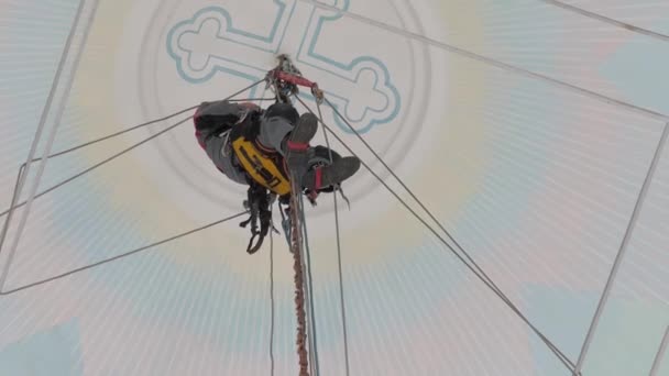 Industrial climber in equipment for high-altitude work working at high altitude in a church building. on the climber s belt carabiners. climber high-altitude installation of chandelier and lighting. — Stock Video
