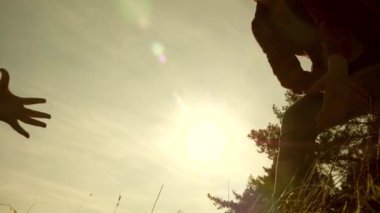Gezginler takım çalışması. Sırt çantalı bir turist ellerini uzatarak dağa tırmanmaya yardım eder. Çocuklarla gün batımında seyahat eden turist ailesi.