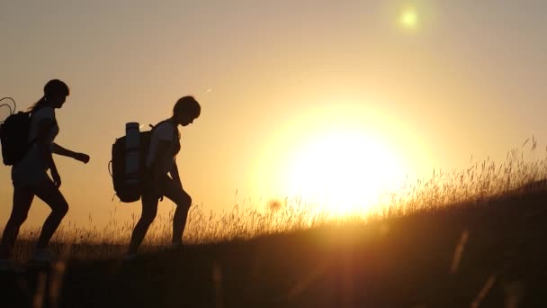 Trabajo en equipo turístico. Los viajeros niños y mamá con mochilas escalan la montaña contra el telón de fondo del hermoso sol. Familia de turistas con niños viajando al atardecer. movimiento a la victoria . — Vídeo de stock