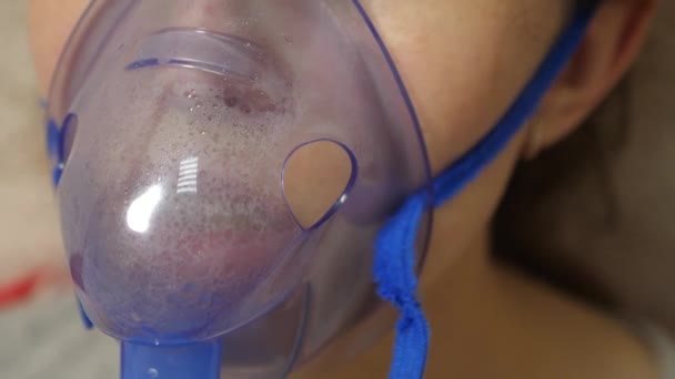 Tratamento da tosse. Close-up. Uma mulher doente com uma máscara é inalada. Uma rapariga com uma máscara azul de hospital. Tratamento de vapores inalatórios para bronquite . — Vídeo de Stock