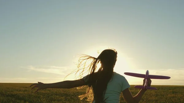Happy girl runs with a toy airplane on a field in the sunset light. children play toy airplane. teenager dreams of flying and becoming pilot. the girl wants to become pilot and astronaut. Slow motion — Stock Photo, Image