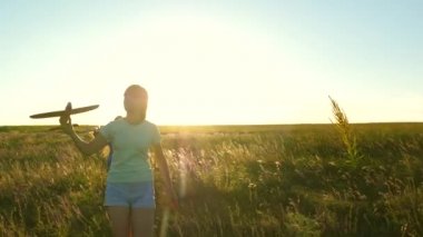 Uçma hayalleri. Mutlu çocukluk kavramı. Gün batımında iki kız bir oyuncak uçakla oynuyor. Güneşin arka planındaki çocuklar ellerinde bir uçakla. Uçakta oynayan çocukların silueti.