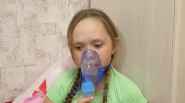 Tabletli çocuk hasta ve astım spreyinden nefes alıyor. Yakın plan. Hastanede yüzünde solunum maskesiyle tedavi edilen küçük bir kız. Yürümeye başlayan çocuk, solunum buharı soluyarak grip tedavisi görüyor..