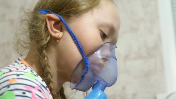 A tablettás gyermek beteg, és inhalátoron keresztül lélegzik. Közelkép. Egy kislány, akit inhalációs maszkkal kezeltek az arcán a kórházban. A kisgyermek az influenzát inhalációs gőz belélegzésével kezeli. — Stock videók