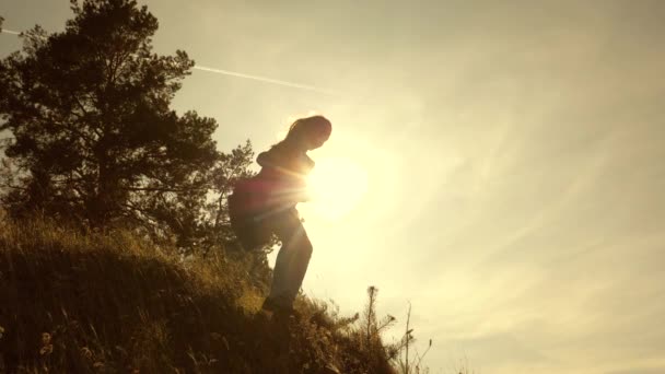 Hiker Girl. Traveler girls descend from the mountain. Family of tourists traveling at sunset. sisters with backpacks travel down the hill in the sun. tourists teamwork — Stock Video