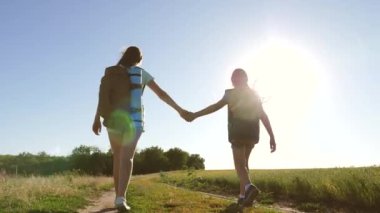 Takım çalışması turistleri. Kadın gezginler kırsalda bir yolda yürürler. Yaz parkındaki mutlu yürüyüşçü kız. Mutlu kız gezginler sırt çantalarıyla gezerler. Tatildeki genç kız maceraları.