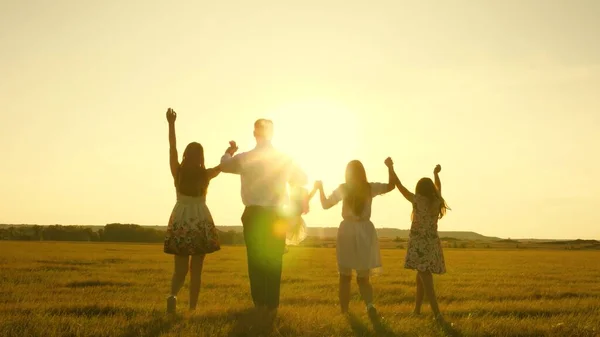 Madre, padre e hija pequeña con hermanas caminando en el campo bajo el sol. Feliz familia joven. Los niños, papá y mamá juegan en el prado bajo el sol. El concepto de una familia feliz . —  Fotos de Stock