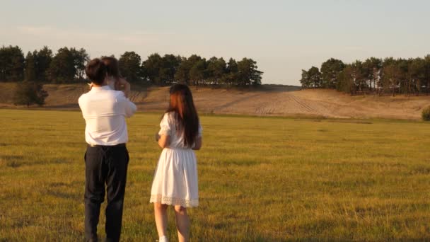 Concepto de una infancia feliz. niño, papá y mamá juegan en el prado bajo el sol. madre, padre e hija pequeña caminando en un campo bajo el sol. Feliz familia joven. concepto de una familia feliz . — Vídeos de Stock