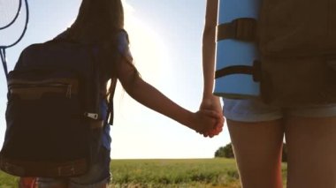 Turizm ve seyahat kavramı. Kızlar, kadın gezginler el ele tutuşur. Yakın plan. Takım çalışması turistleri. Kadın gezginler kırsalda bir yolda yürürler. Kız gezginler sırt çantalarıyla tarlaya giderler..